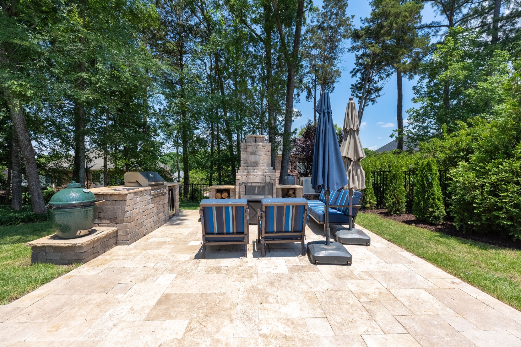Outdoor kitchen and fireplace lounge with stone terrace seating.