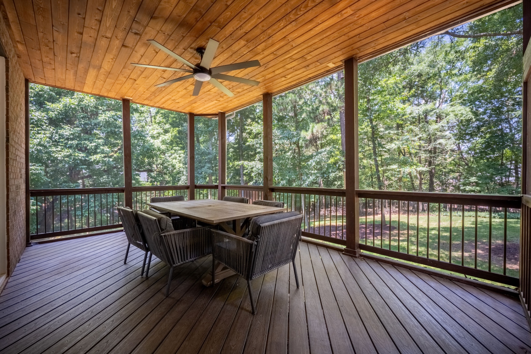 Screened porch with vaulted wood ceiling, ceiling fan, and composite decking.