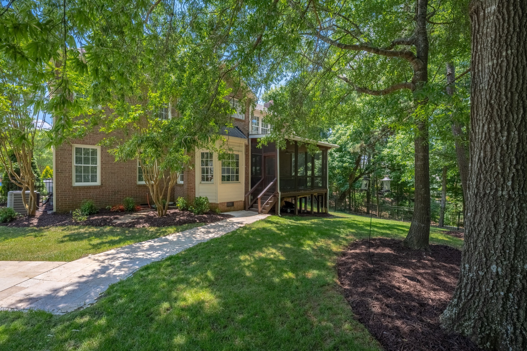 Rear exterior highlighting the screened porch and landscaped backyard approach.