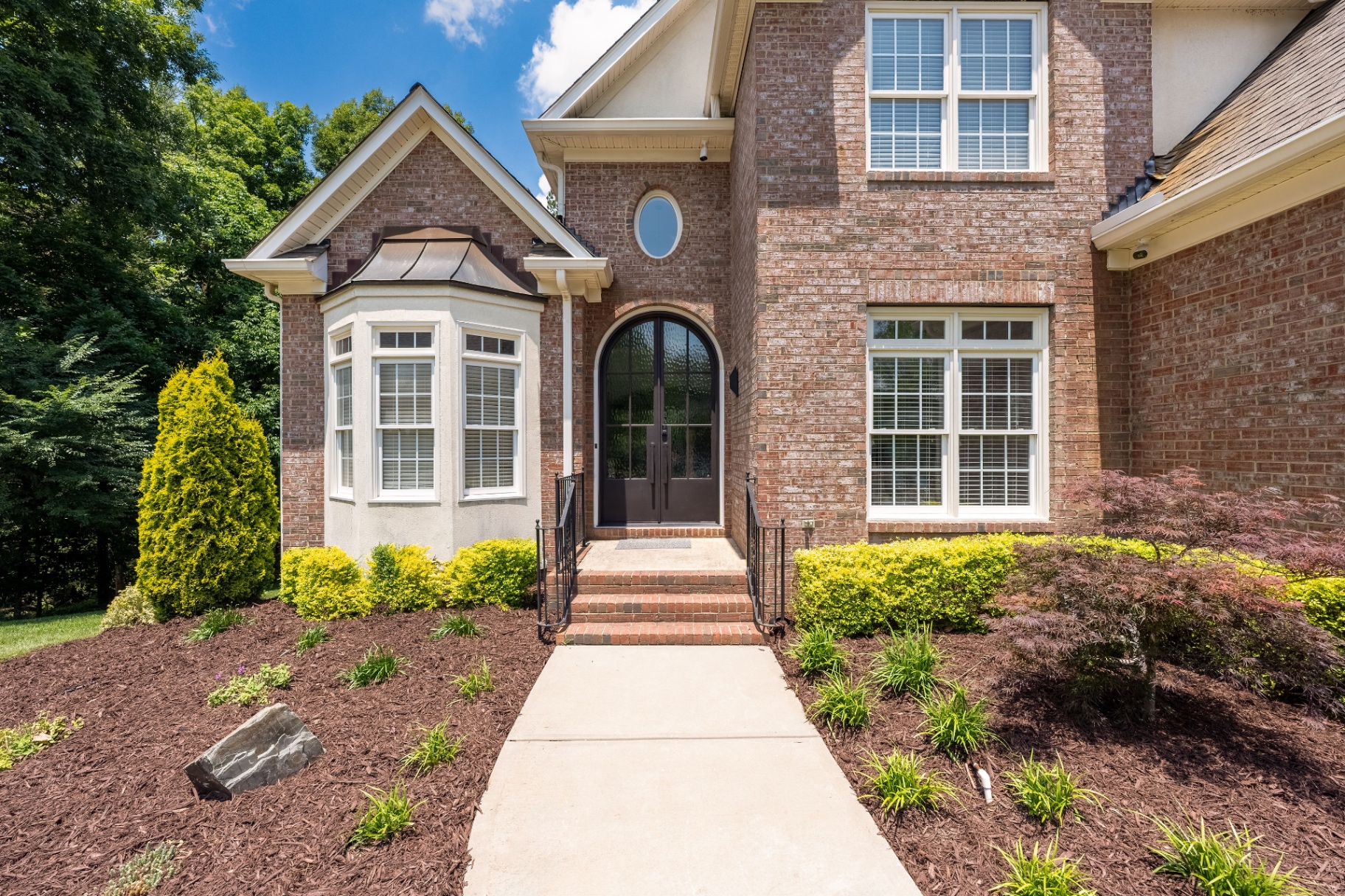 Front entry detail showcasing the arched steel front door and brick façade.